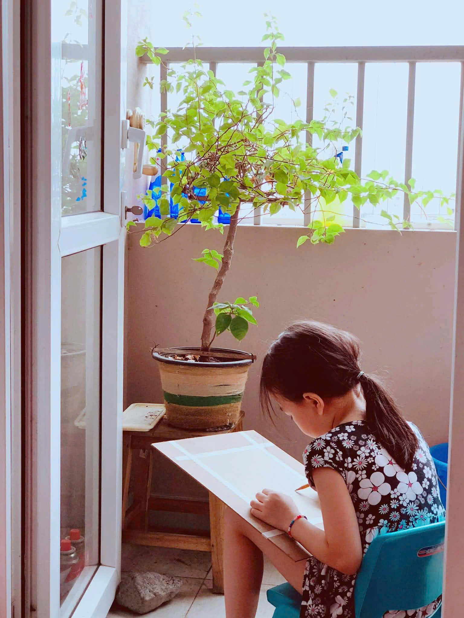 Nhinh đang vẽ bên cửa sổ